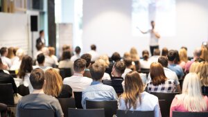 Vortragender vor sitzendem Publikum