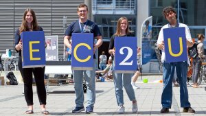 Vier Personen halten Buchstabenwürfel in der Hand